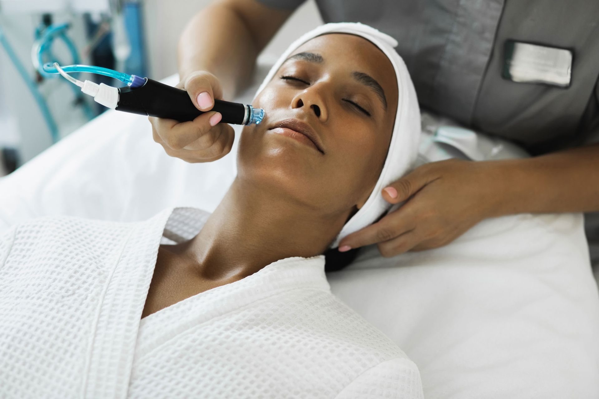 Woman receiving facial treatment in a spa, device applied to her face.